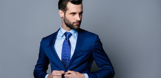 Portrait Of Serious Fashionable Handsome Man In Blue Suit And Tie Buttoning Jacket